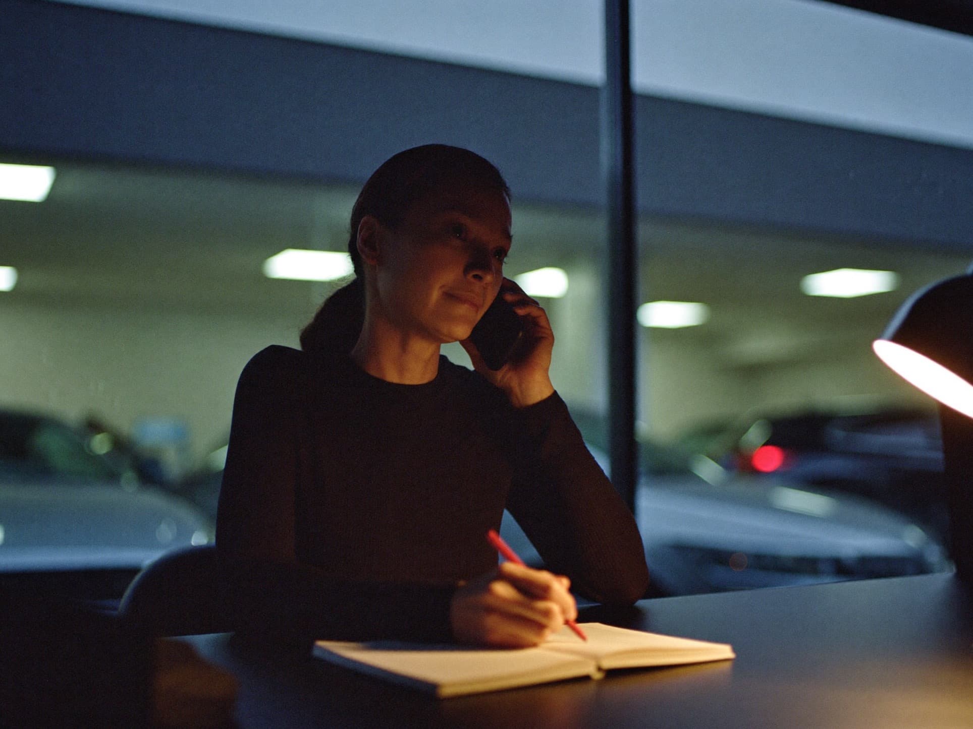 A salesperson on a phone call at her desk, making a note